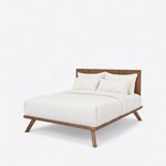 Diagonal angled view showing the left side of a contemporary platform bed, with a solid panel headboard and splayed legs.