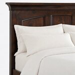 Headboard close-up of a classic panel bed, showing coved crown molding above arched raised panels and a square stile.