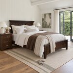 Diagonal angled room view showing the right side of a classic panel bed with a low arched footboard, in a shiplap bedroom.