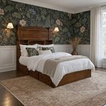 Diagonal angled room view showing the right side of a bookcase storage bed with drawers, in a floral-wallpapered bedroom.