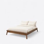 Diagonal angled view showing the left side of a mid-century platform bed, with no headboard and splayed legs.