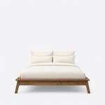 Front view of a mid-century platform bed, showing a low frame with an overhanging rim on splayed legs and no headboard.