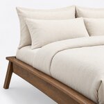 Head end close-up of a mid-century platform bed, showing the bare head corner, the rimmed frame edge and a splayed leg.