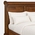 Headboard close-up of a traditional sleigh bed, showing the rolled crest, a grooved scroll stile and recessed flat panels.