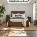 Front room view of a traditional sleigh bed with a rolled scroll headboard, in a white plaster bedroom under a skylight.