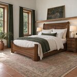 Diagonal angled room view showing the left side of a traditional sleigh bed with a curved footboard, in a tropical bedroom.