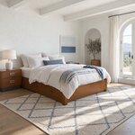 Diagonal angled room view showing the right side of a modern platform bed with side drawers, in a white plaster bedroom.