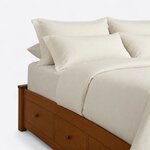 Head end close-up of a modern platform bed, showing a capped square corner post and side drawers with round knobs.