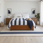 Front room view of a modern platform bed with a low solid footboard and block legs, in a white coastal bedroom.