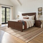 Diagonal angled room view showing the left side of a traditional panel bed with cornice caps, in a white farmhouse bedroom.
