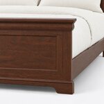 Footboard close-up of a traditional panel bed, showing the molded cornice cap, a recessed panel and a bracket plinth foot.