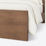 Footboard close-up of a modern panel bed, showing the square-edged slab footboard reaching the floor and a plain side rail.