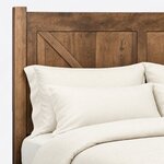Headboard close-up of a rustic panel bed, showing a square post, the top rail and a diagonal brace over vertical planks.