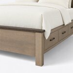 Footboard close-up of a Shaker storage bed, showing the overhanging cap rail, a square corner leg and arched drawer pulls.