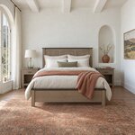 Front room view of a Shaker storage bed with a three-panel headboard, in a white plaster bedroom with an arched niche.