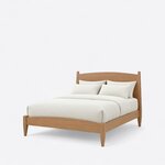 Diagonal angled view showing the left side of a modern panel bed, with an arched headboard and footboard on tapered legs.