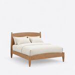 Diagonal angled view showing the right side of a modern panel bed, with an arched headboard and footboard on tapered legs.