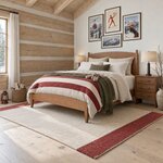 Diagonal angled room view showing the left side of a modern panel bed with an arched headboard, in a log cabin bedroom.