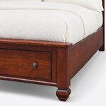 Footboard close-up of a traditional storage bed, showing the overhanging cap rail, square post, bun foot and drawer knob.