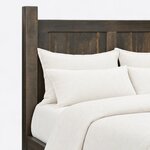 Headboard close-up of a farmhouse panel bed, showing recessed panels framed by flat rails and a thick square post.
