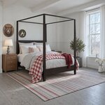 Diagonal angled room view showing the right side of a modern canopy bed with square posts, in a white beamed bedroom.