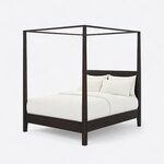 Diagonal angled view showing the left side of a modern canopy bed, with an open canopy frame and a plain panel headboard.