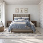 Front room view of a modern upholstered bed with a channel-tufted wingback headboard, in a whitewashed log cabin bedroom.