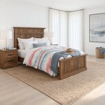 Diagonal angled room view showing the right side of a traditional panel bed with crown caps, in a white coastal bedroom.