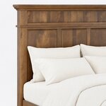 Headboard close-up of a traditional panel bed, showing a crown-molded cap, a vertical plank band and recessed panels.