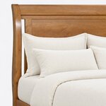 Headboard close-up of a transitional sleigh bed, showing the rolled top rail, a recessed flat panel and a curved side post.