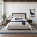 Front room view of a modern upholstered bed with a framed panel headboard, in a white bedroom with a coffered ceiling.