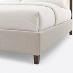 Footboard close-up of a modern upholstered bed, showing a crisp upholstered corner, the flush side rail and a tapered leg.