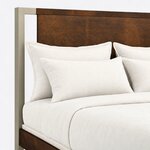 Headboard close-up of a modern panel bed, showing a flat panel under a slim top rail, framed by a square metal post.