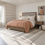 Diagonal angled room view showing the left side of a contemporary upholstered bed with button tufting, in a log cabin room.