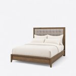 Diagonal angled view showing the left side of a contemporary upholstered bed, with a wide-framed button-tufted headboard.