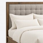 Headboard close-up of a contemporary upholstered bed, showing deep button tufting set inside a wide mitered frame.