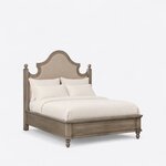 Diagonal angled view showing the right side of a farmhouse upholstered bed, with a scalloped headboard and nailhead trim.