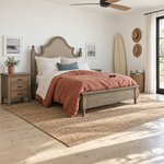Diagonal angled room view showing the right side of a farmhouse upholstered bed with nailhead trim, in a beach house bedroom.