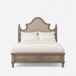 Front view of a farmhouse upholstered bed, showing a tall scalloped headboard, ball-finial posts and a low panel footboard.