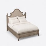 High angled view of a farmhouse upholstered bed, looking down on the scalloped headboard, side rails and low panel footboard.