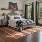 Diagonal angled room view showing the right side of a farmhouse panel bed with a scalloped headboard, in a tropical bedroom.