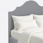 Headboard close-up of a farmhouse panel bed, showing horizontal plank grooves beneath the arched scalloped crest.