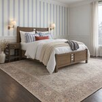 Diagonal angled room view showing the right side of a modern panel bed with cutout panels, in a striped wallpaper bedroom.