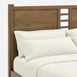 Headboard close-up of a modern panel bed, showing a recessed panel beside a ladder-style cutout, a square post and top rail.