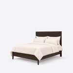 Diagonal angled view showing the left side of a minimalist panel bed, with a tall two-panel headboard and tapered legs.