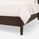 Footboard close-up of a minimalist panel bed, showing the plain low footboard, a square tapered leg and the side rail joint.