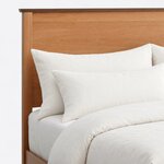 Headboard close-up of a mid-century panel bed, showing a flat panel framed by square posts under a thin overhanging cap.