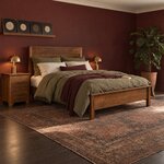 Diagonal angled room view showing the right side of a transitional panel bed with a low footboard, in a burgundy bedroom.