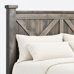 Headboard close-up of a rustic panel bed, showing V-braced vertical planks under a top rail and a capped square post.