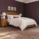 Diagonal angled room view showing the right side of a transitional panel bed with square posts, in a plum-paneled bedroom.